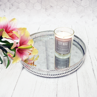 Decorative Circular Nickel Mirror Effect Tray with a Soy Wax candle and pink flowers on a white background