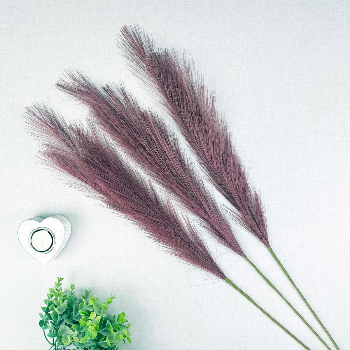 Scarlet Red Faux Pampas Grass Stem with a heart tealight holder and greenery, on a white background.