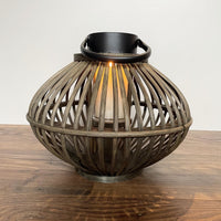 Bamboo Style Candle Lantern with candle lit, on wooden floor