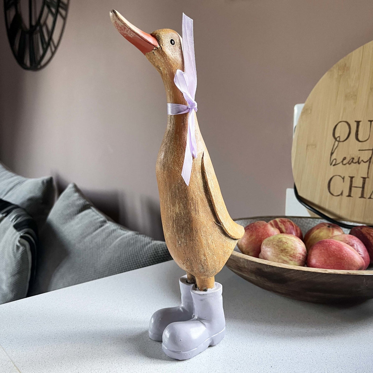 Darcey Duck on kitchen bench with fruit bowl full of apples in behind her