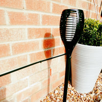 Flame Effect Solar Powered Garden Light in gravel next to planter