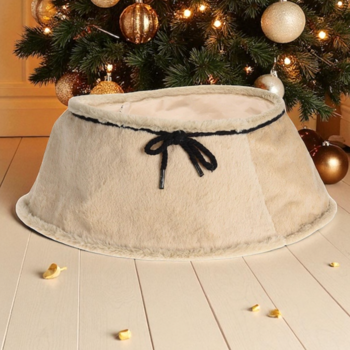 Beige tree skirt with a black bow in front of a decorated Christmas tree.