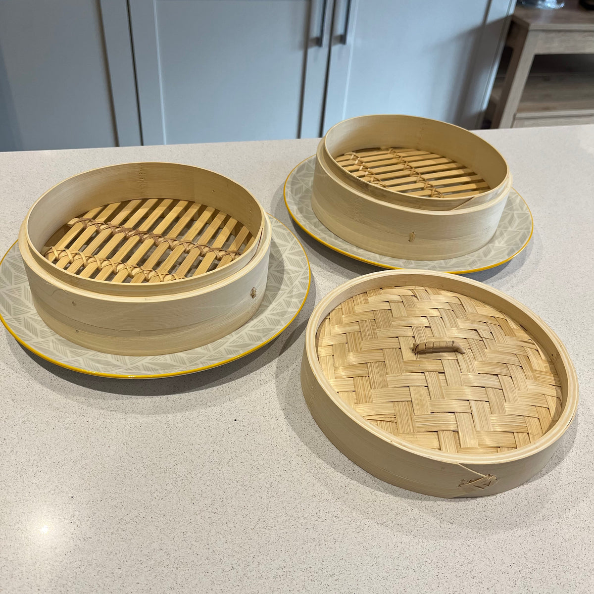 Two-Tier Bamboo Steamer on grey and yellow plates on grey kitchen bench