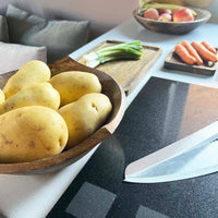 Large Puncta Mango Wood Bowl on kitchen bench with utensils  and potatoes in
