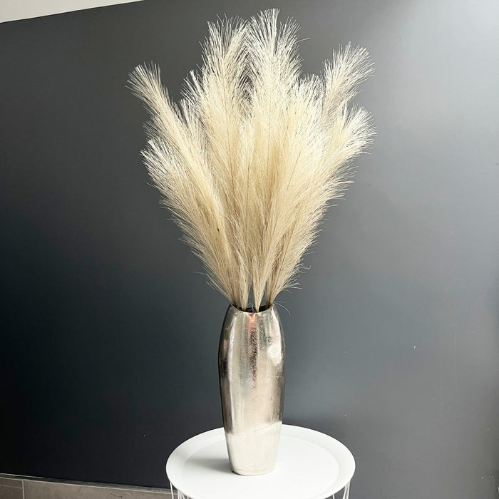 Bleached Faux Pampas Grass Stem in chrome vase, one white table, with dark grey background.