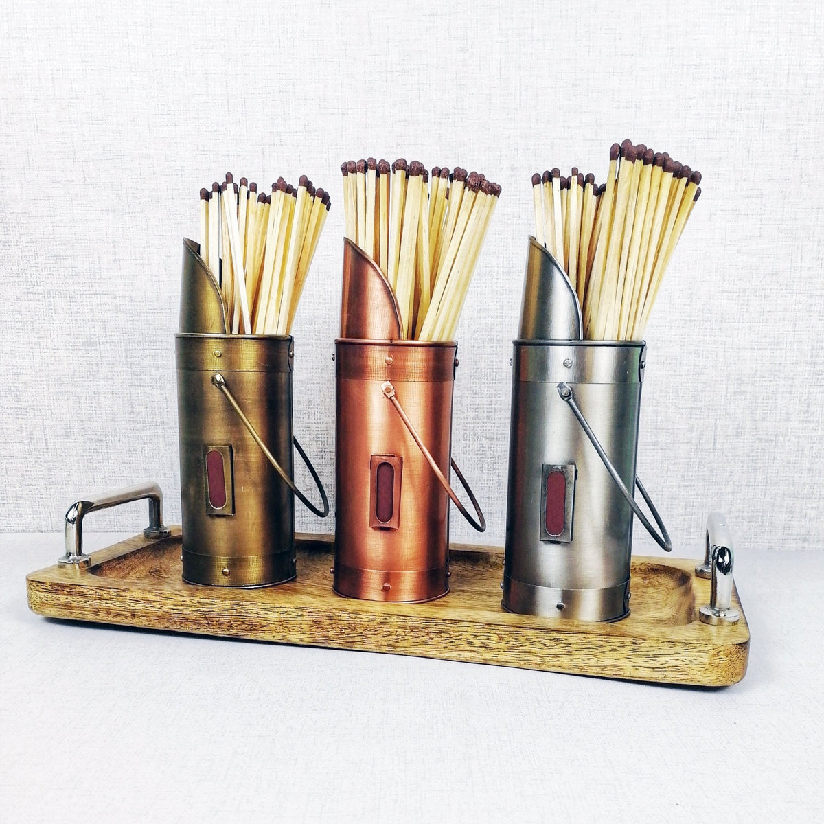 Matchstick holders bronze pewter copper on wooden tray against grey background