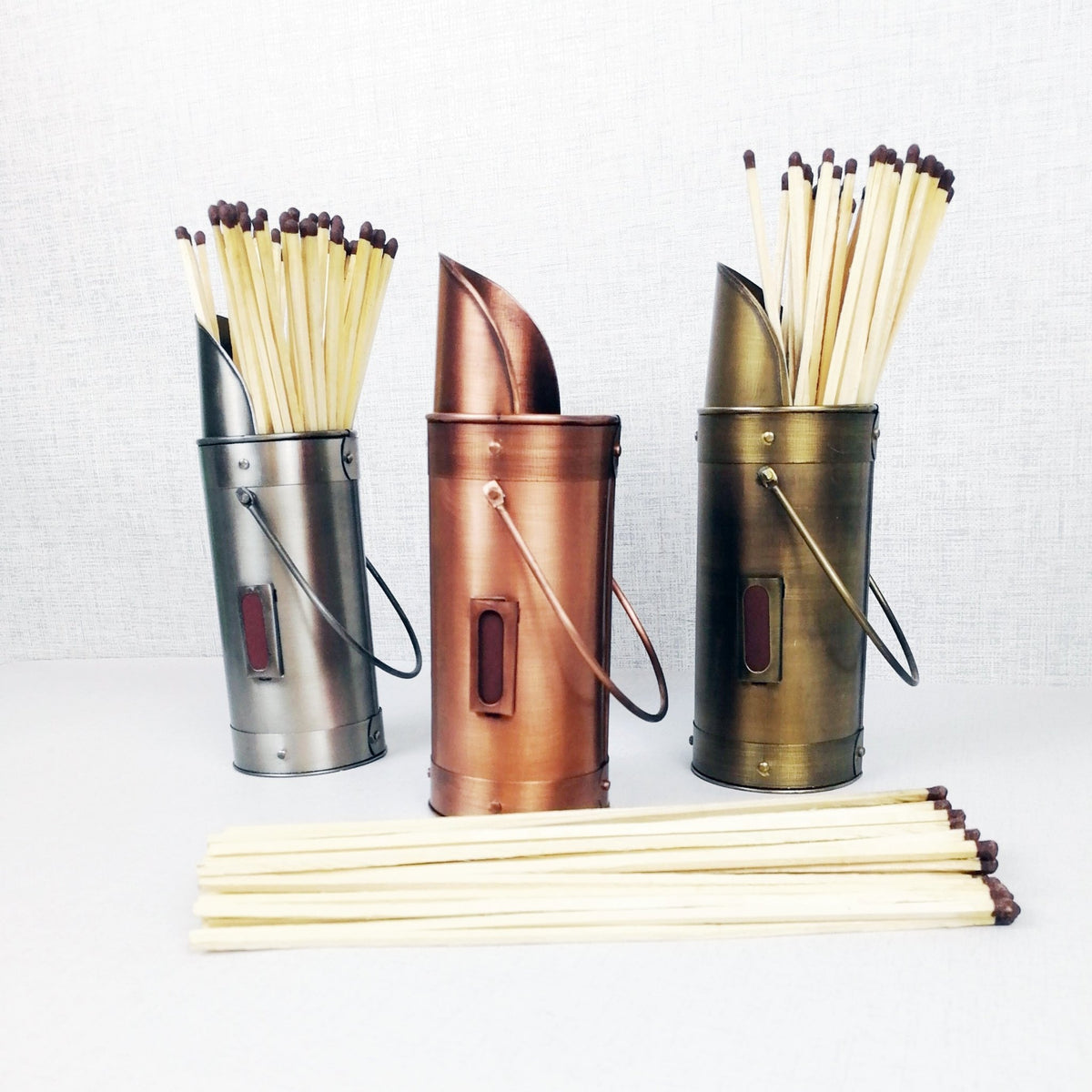 Matchstick holders bronze pewter copper with matches against grey background