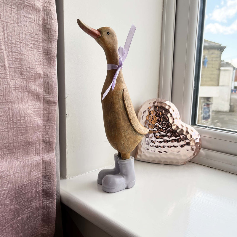 Darcey Duck on window sill with pink curtains and a pink heart decor