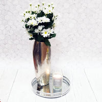 Decorative Circular Nickel Mirror Effect Tray with a Soy Wax candle and a large silver vase with white flowers on a white background