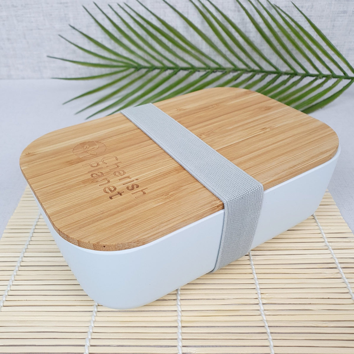 White Eco Bamboo & Wheat Fibre Lunch / Bento Box, on bamboo mat, on white background with greenery