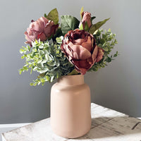 Full leaf sprays with dusty pinks roses in a pink vase.