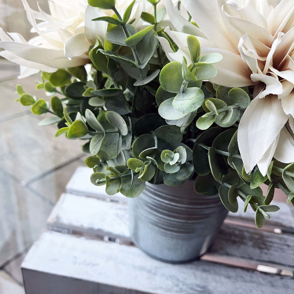 Full leaf sprays with dusty pinks roses in a silver vase with cafe au lait flowers.