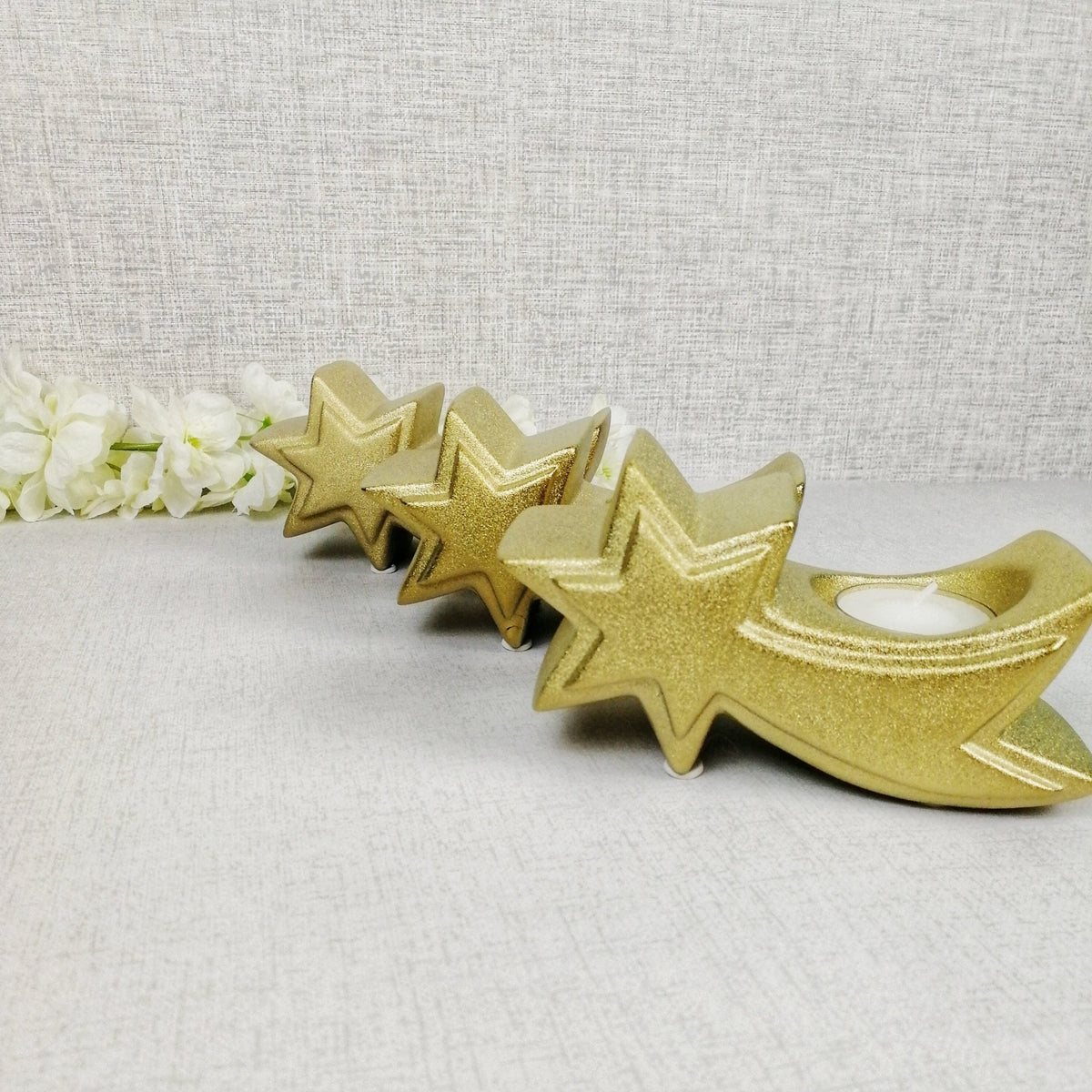 Set of three gold star tea light candle holders in a row