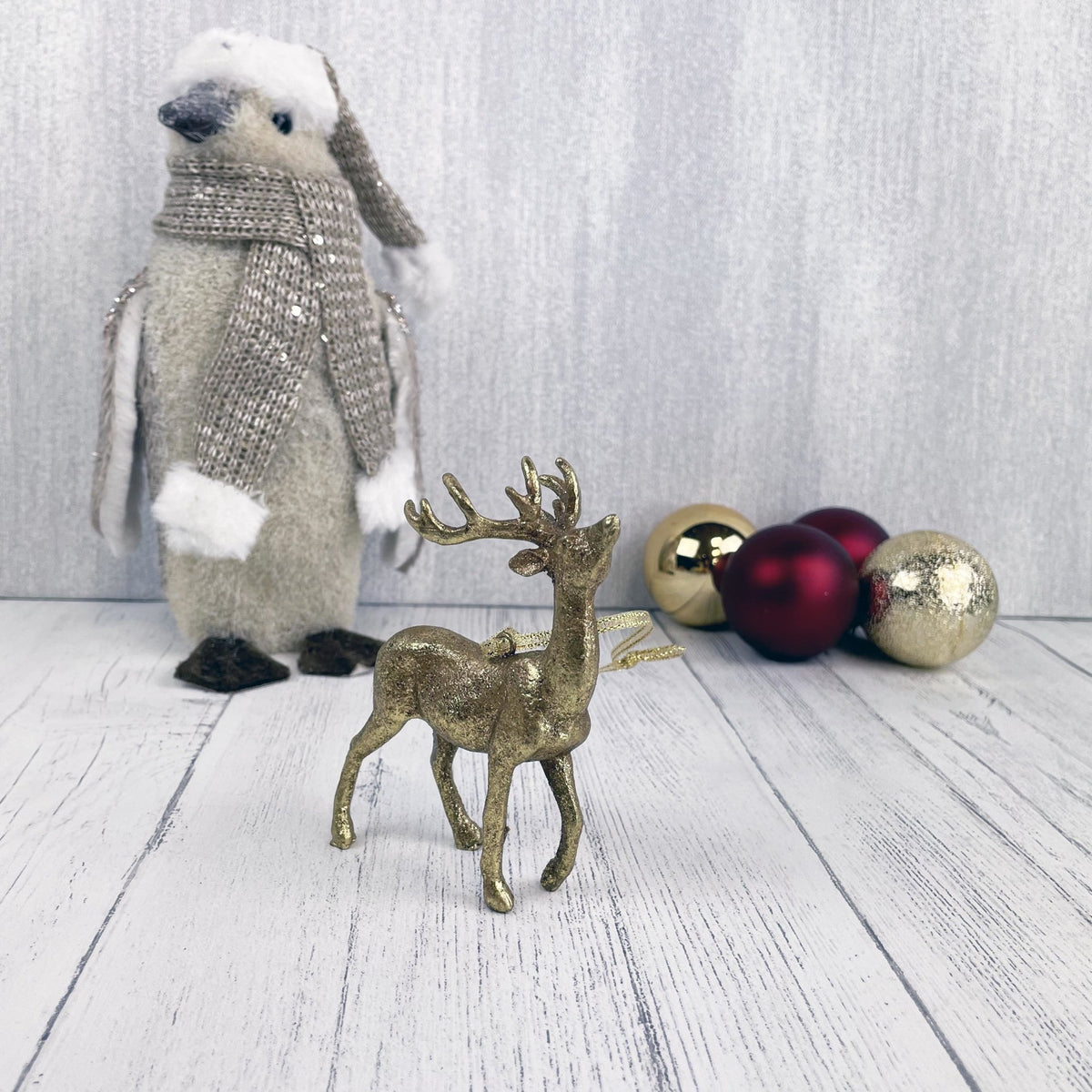 Hanging Gold Stag Christmas Tree Decoration with penguin and baubles in the background