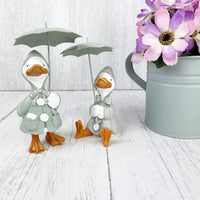Happy Rainy Ducks ornament set of 2 next to planter with purple flowers