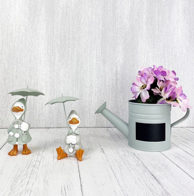 Happy Rainy Ducks ornament set of 2 next to watering can planter with purple flowers in.