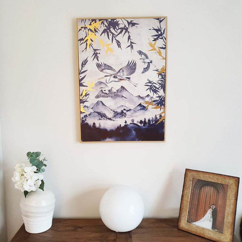 Japanese Gold Leaf Heron Canvas Print on white wall with a vase, light and photo frame displayed on sideboard below