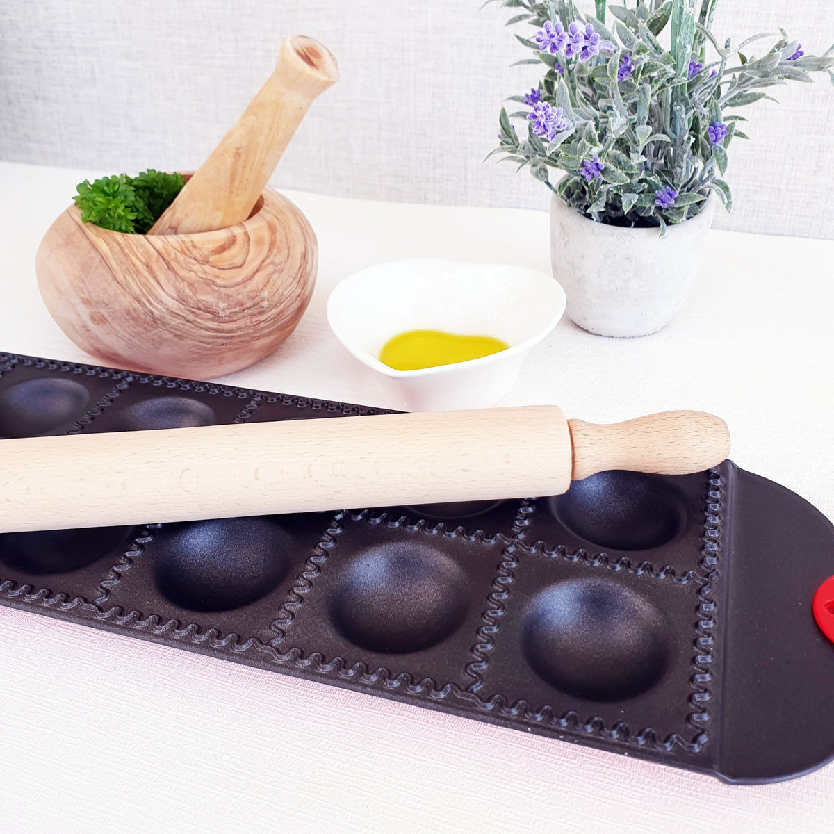 Ravioli Cutting Tray with rollin gpin on top and pestle and mortar in background
