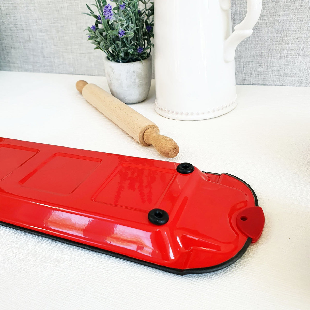 Ravioli Cutting Tray Base Red with rolling pin and plant on white surface