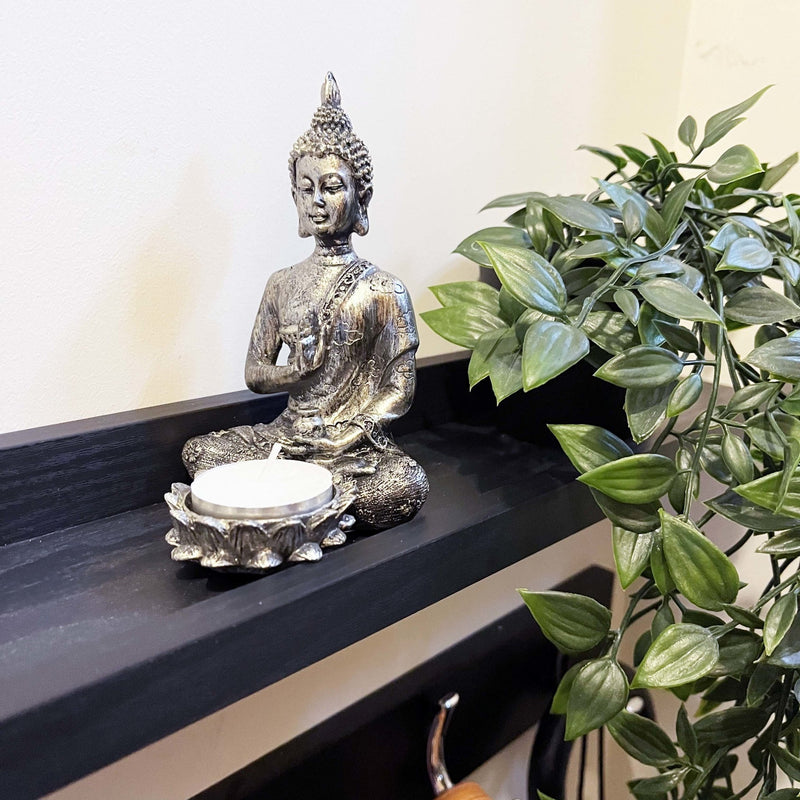 Silver Effect Buddha Candle Holder on black shelving with trailing plant