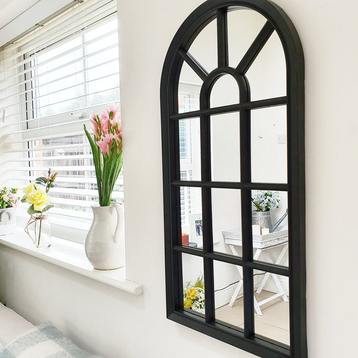 Velit Window style wall mirror in black on a white kitchen wall with a windowsill full of beautiful pink and yellow flowers